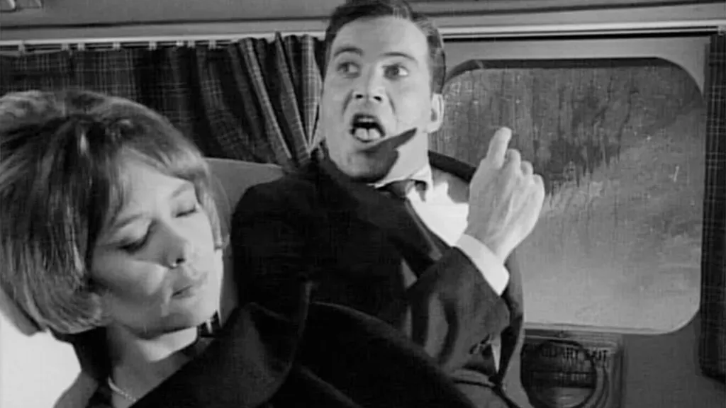 Cena do episódio 'Nightmare at 20,000 Feet' de The Twilight Zone, com um homem olhando para uma criatura na asa de um avião.